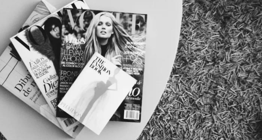 black and white photo of several vogue magazines on a table