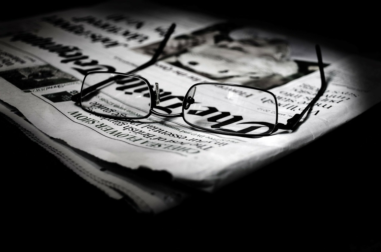 glasses laying on top of a folded newspaper