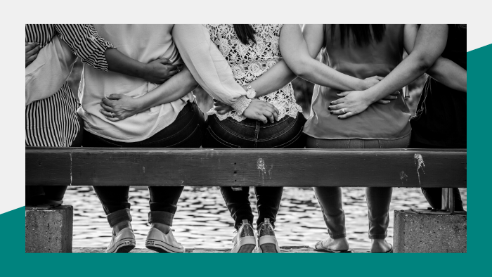 Group of women sitting on a bench with arms wrapped around each other