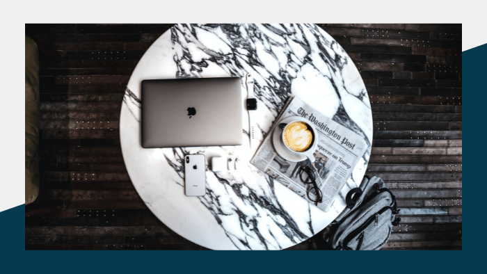 Laptop, smartphone, coffee and a newspaper on a marble tabletop