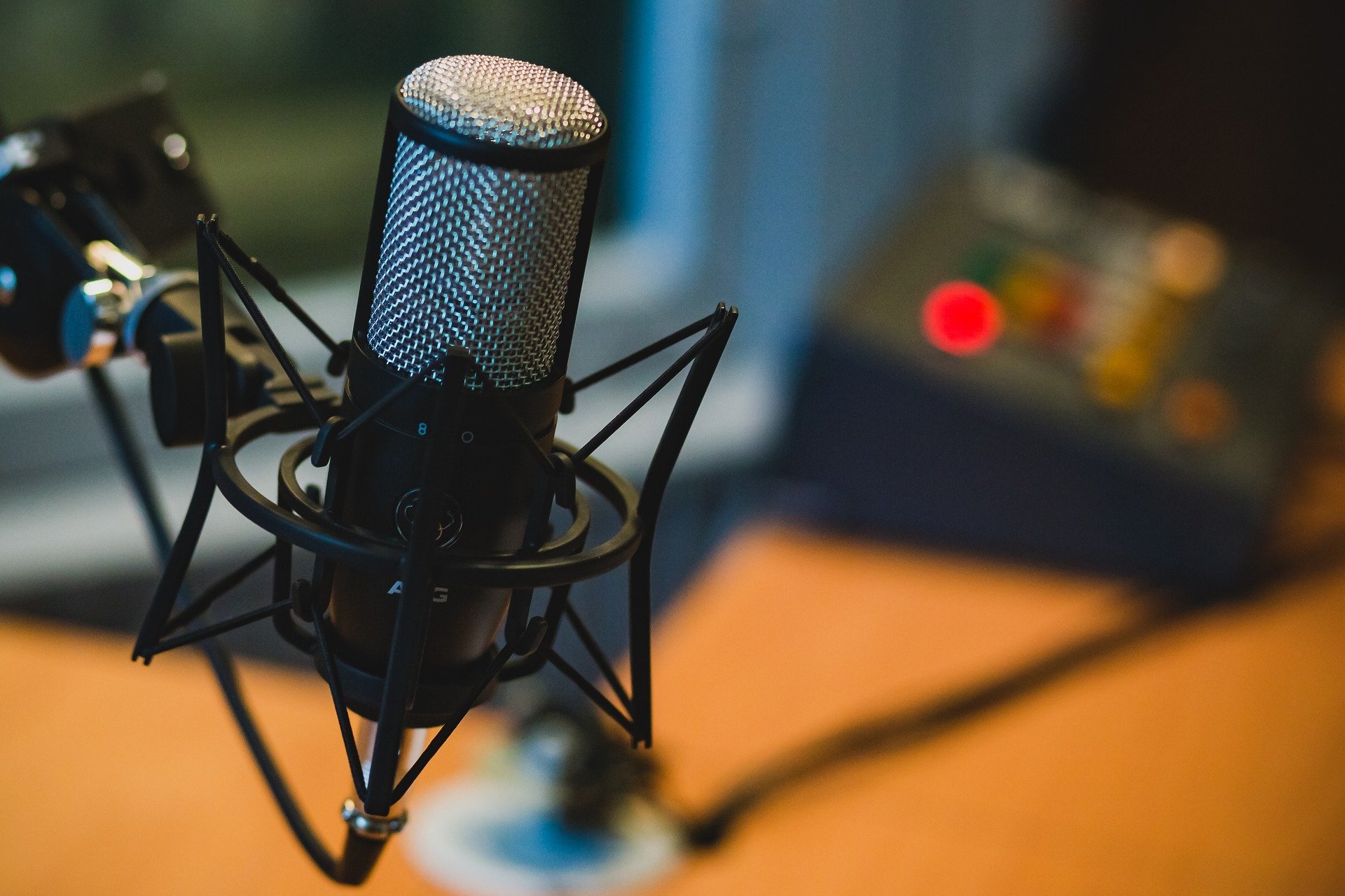 a podcast microphone on a table with podcast equipment behind it